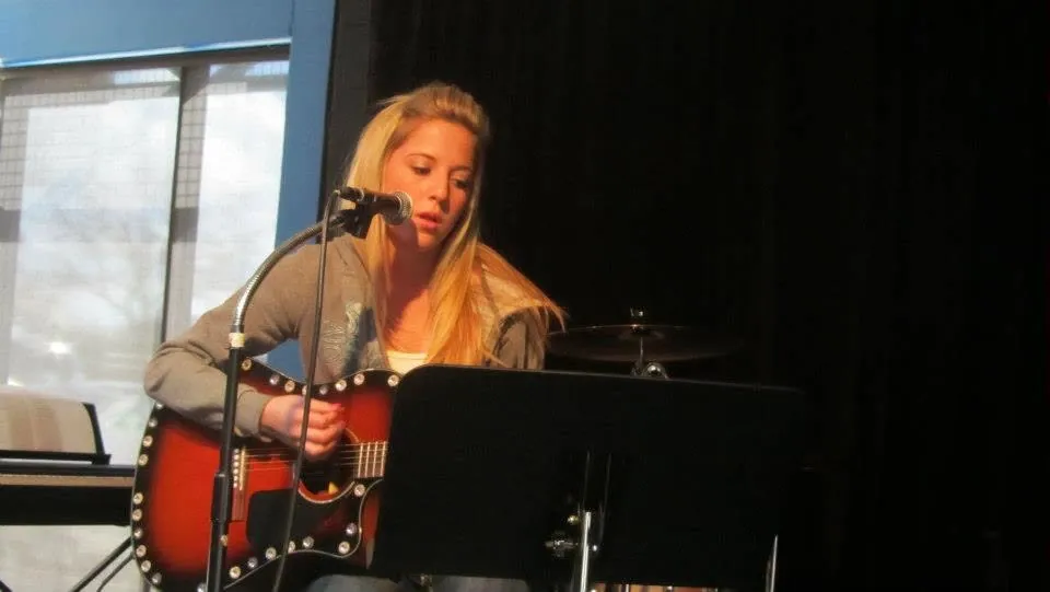 A teen Mojo's Music Academy student performing a guitar and vocal solo at a recital