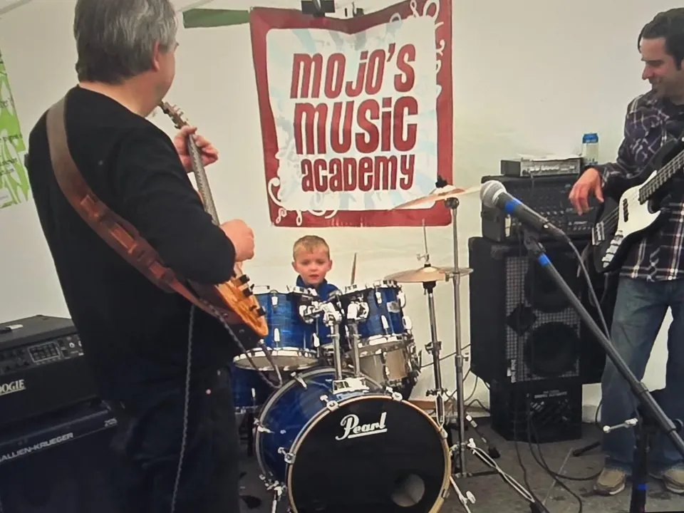 Jasper Allison as a young drum student playing with teachers at a Mojo's Music Academy booth