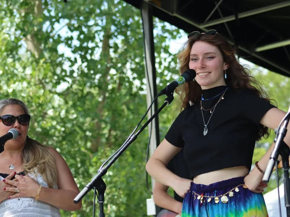 Dakota Allison smiling on stage next to her teacher Jessica Rogalski