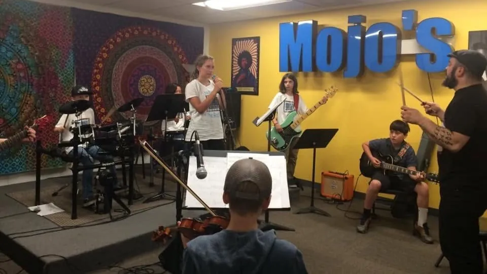 A band of Mojo's students with a vocalist performing at a recital
