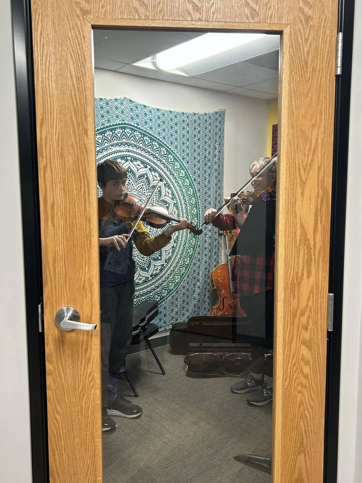 An instructor and student playing violin together in a private lesson room at Mojo's Music Academy