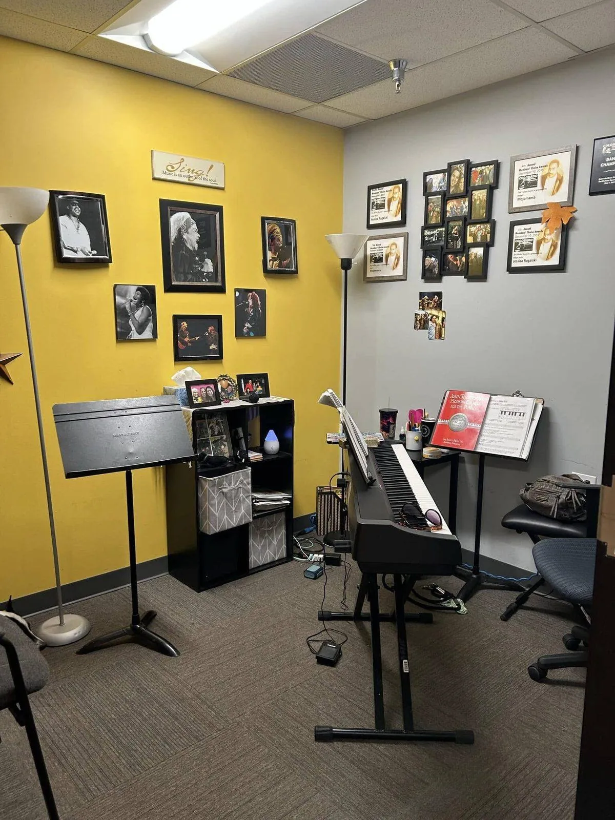 An instructor's private studio room at Mojo's Music Academy, with a piano and instructor's own performance memorabilia on the walls
