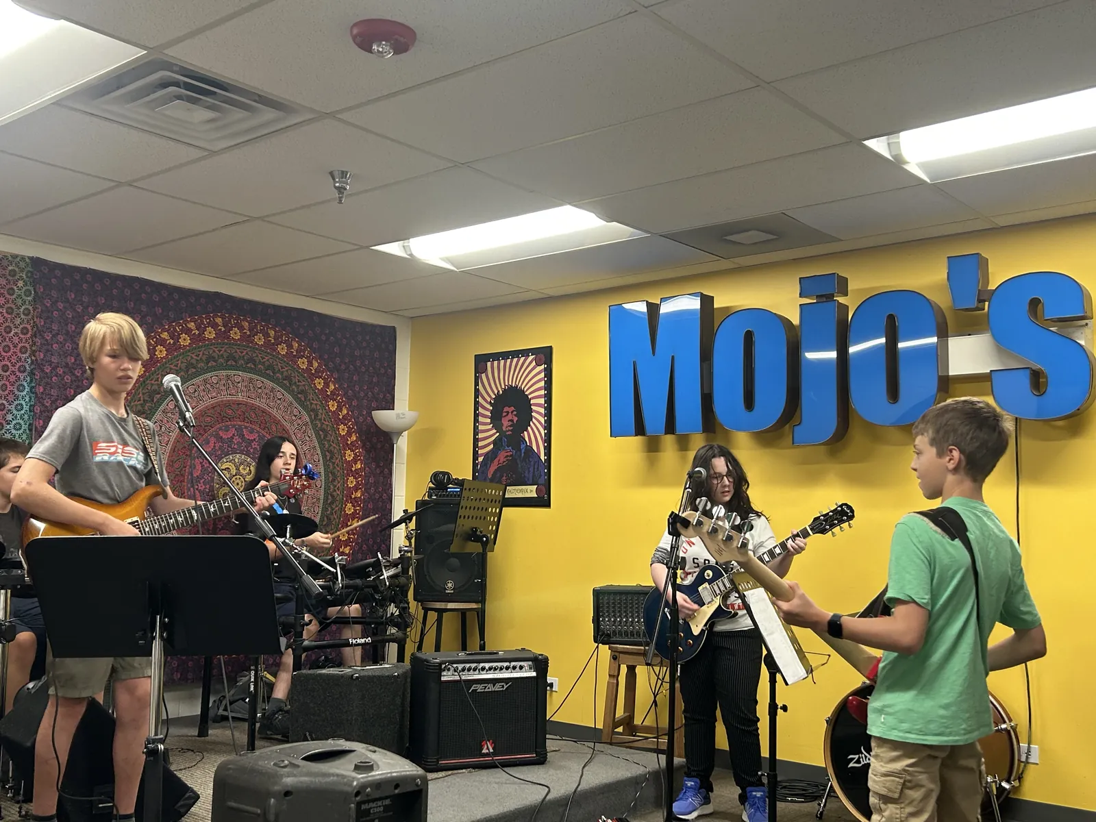 Students practicing together in a rehearsal room at Mojo's Music Academy