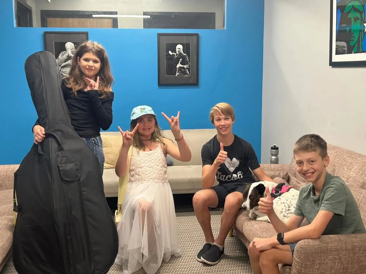 Four smiling Mojo's Music Academy students posing together on a couch in the Longmont studio