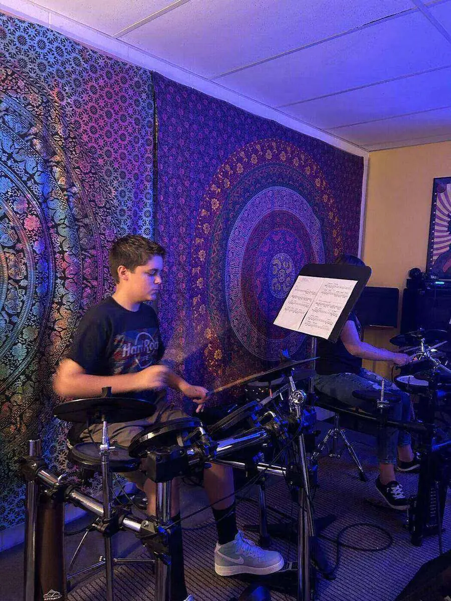 Student playing drums in a private lesson room at Mojo's Music Academy