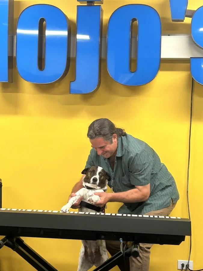 Paul Rogalski at the keyboard with the studio dog, inside Mojo's Music Academy in Longmont, CO
