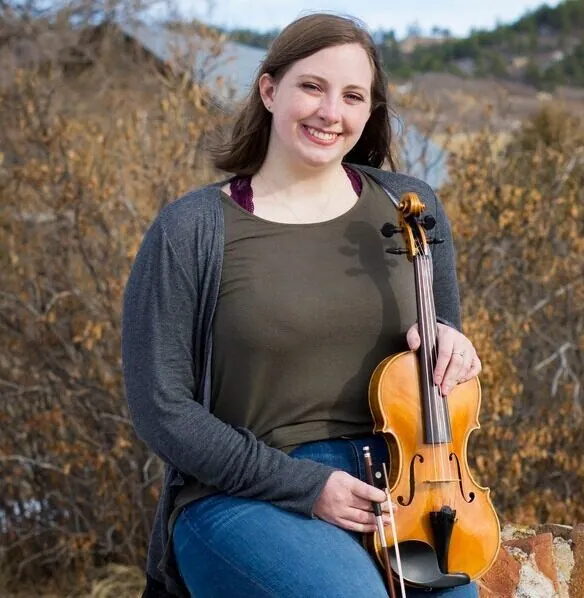 Holly Petersen holding a violin, violin, viola and cello instructor at Mojo's Music Academy in Longmont, CO